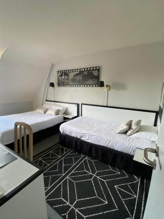 ルーアンにあるオテル セリーヌ - オテル ドゥ ラ ガールのベッド2台とテーブルが備わる客室です。