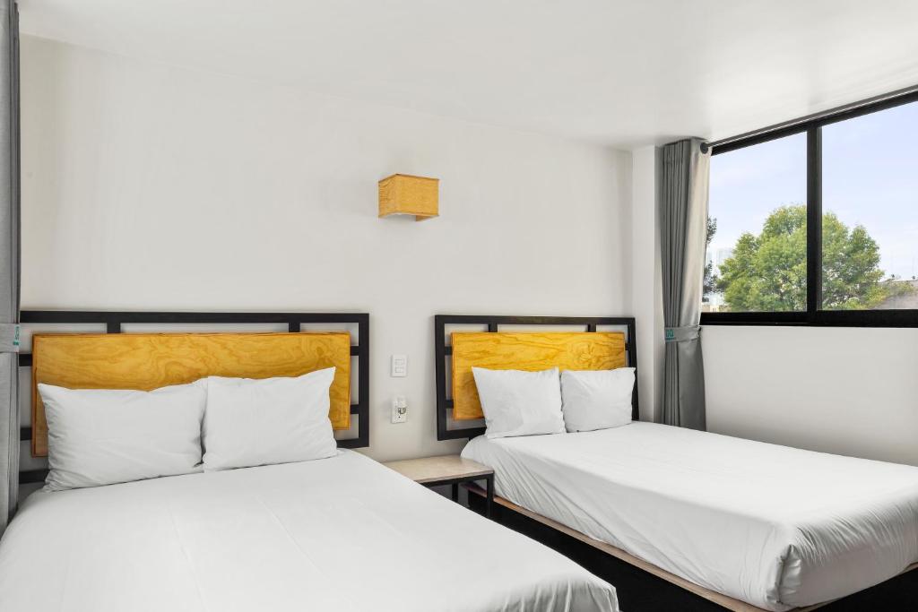 twee bedden in een kamer met twee ramen bij Lago Zirahuén By HomiRent in Mexico-Stad