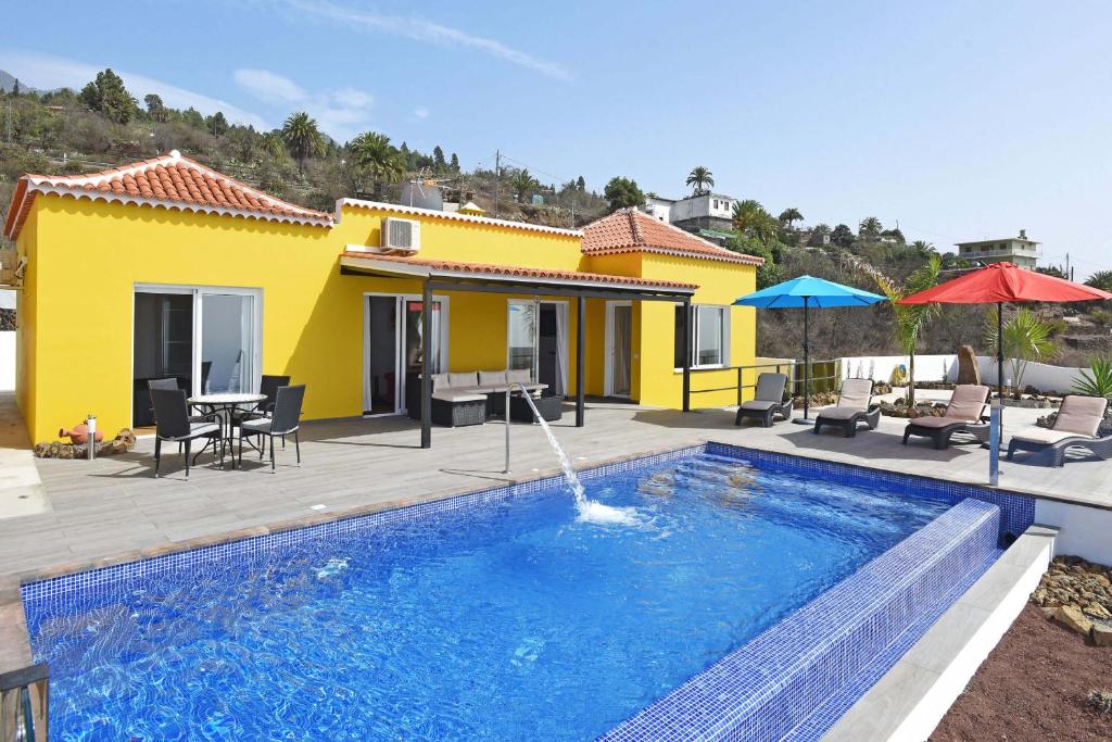 a swimming pool in front of a yellow house at Casa Diamante in Tijarafe