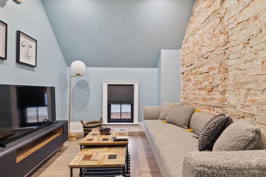 ein Wohnzimmer mit Sofa und Ziegelwand in der Unterkunft Luxury Contemporary Condo in Downtown Collingwood 97044 in Collingwood