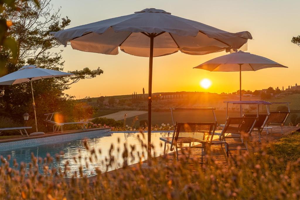 una piscina con sillas y sombrillas frente a la puesta de sol en Villa ALTA, en Villastrada