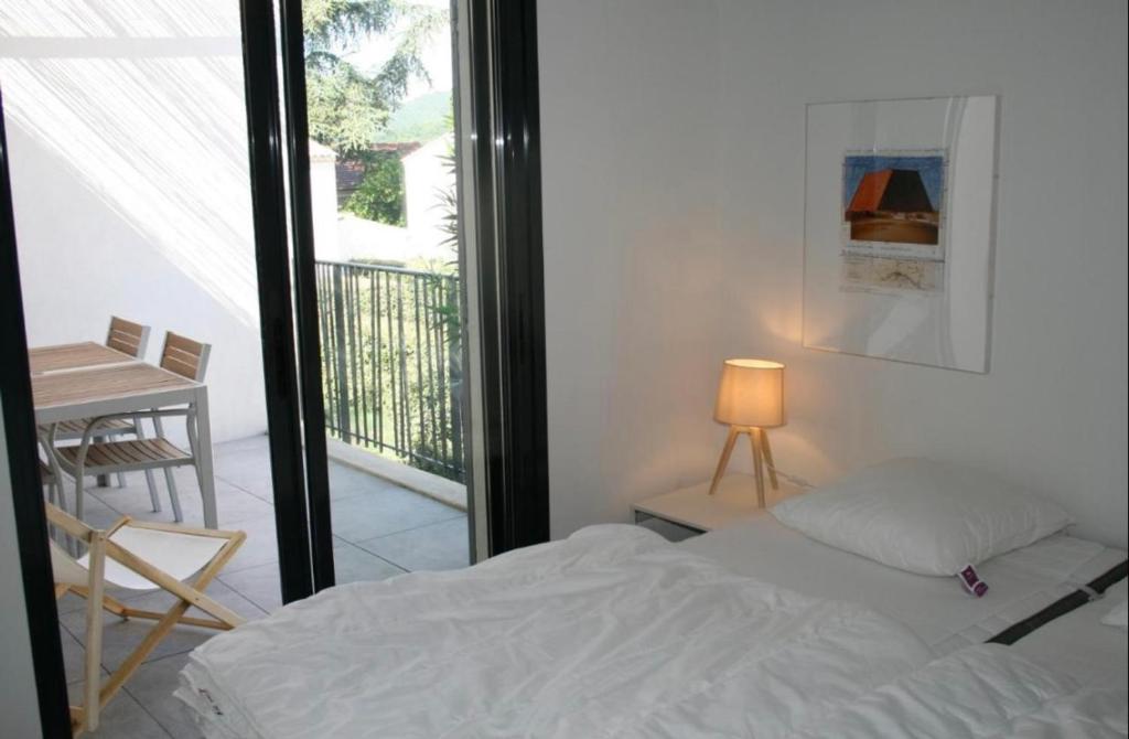 a bedroom with a bed and a balcony with a table at Les Cyclistes : appartement Vintoux in Malaucène