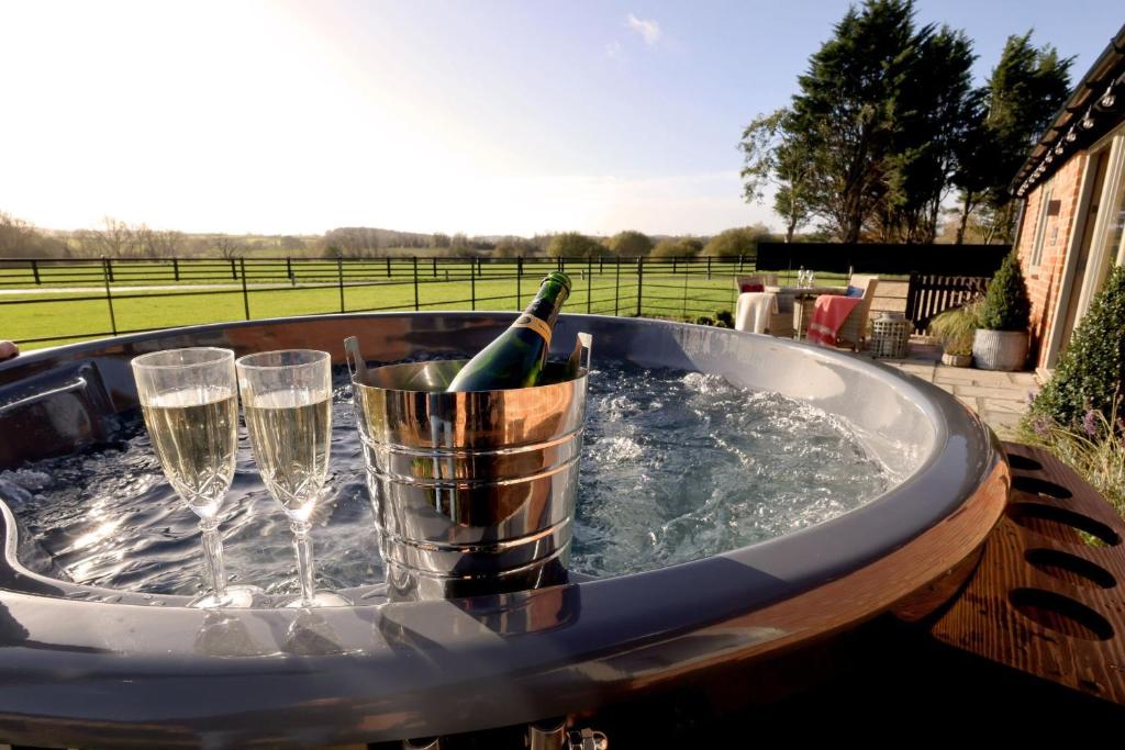 bañera de hidromasaje con copas de vino y botella de champán en Stable Barn 