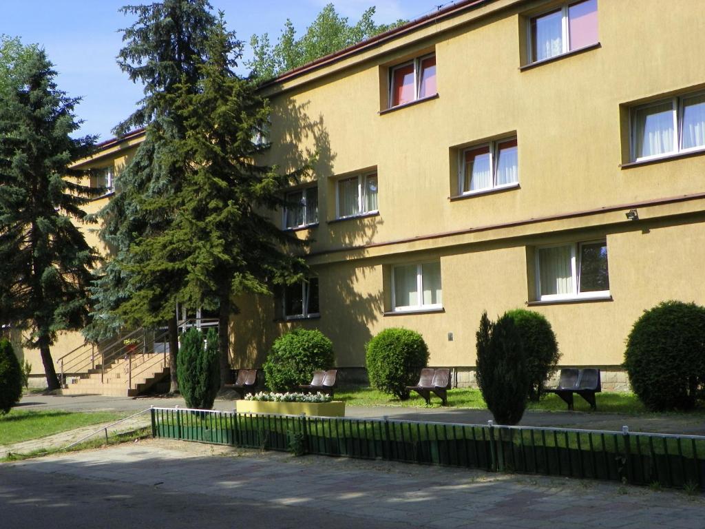 żółty budynek z ławkami przed nim w obiekcie Hotel Skaut w mieście Chorzów