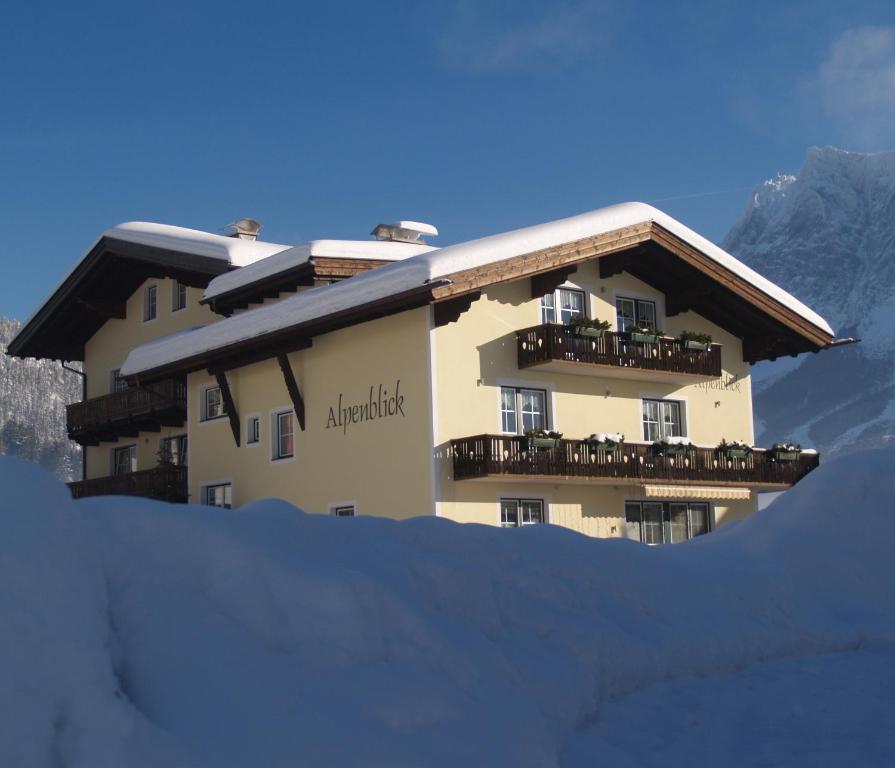 un edificio en una montaña con nieve en el suelo en B&B Gästehaus Alpenblick, en Lermoos