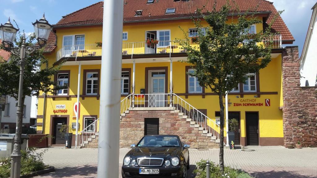 ein vor einem gelben Gebäude geparkt in der Unterkunft Hotel Zum Schwanen in Leimen
