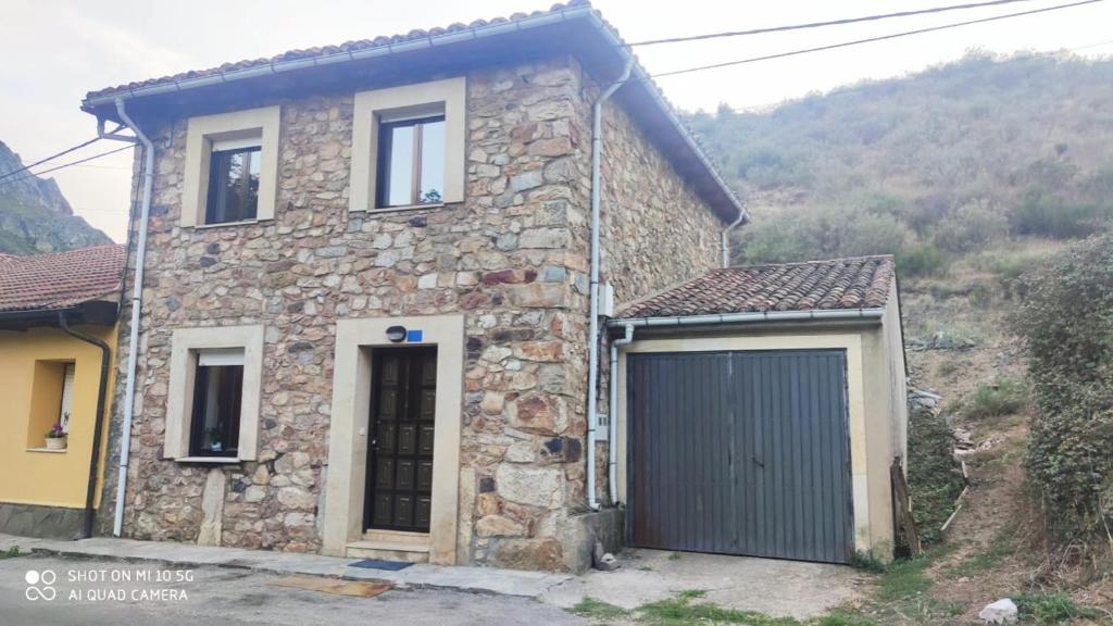 a stone house with a garage in front of a mountain at La Casa de Quico 