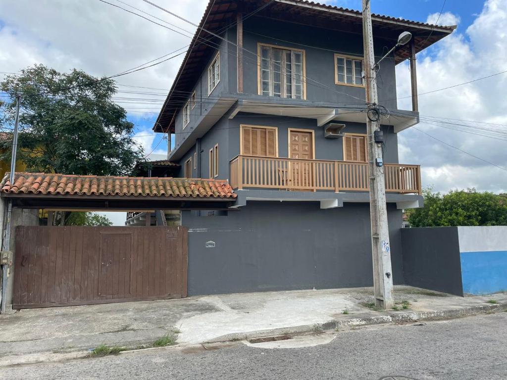 a blue house with a porch and a fence at Quitinete família standard 202 in Cabo Frio