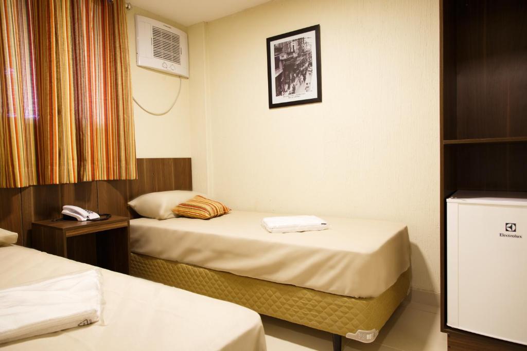 a hotel room with two beds and a window at Downtown Santana Hotel in Rio de Janeiro