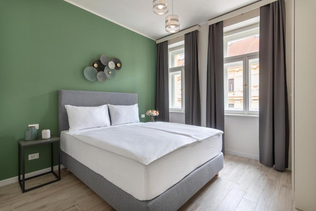 1 dormitorio con cama blanca y paredes verdes en Kinsky Garden Apartments and Suites, en Praga