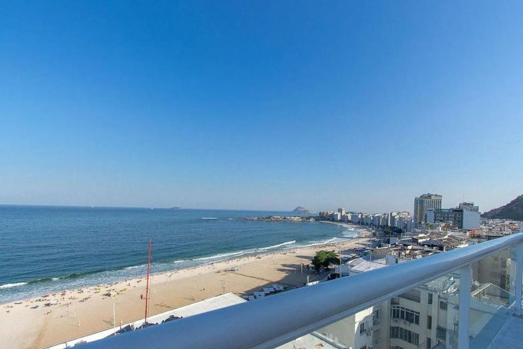 a view of a beach and the ocean from a balcony at Flat Praia de Copacabana - Pé na Areia in Rio de Janeiro
