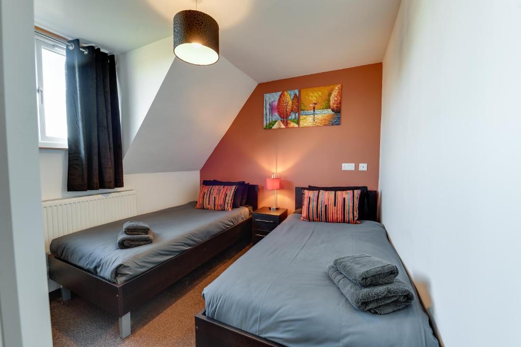 1 dormitorio con 2 camas y ventana en 3 Bedroom Home l Free Parking l Long and Short Term Stays, en Wigan