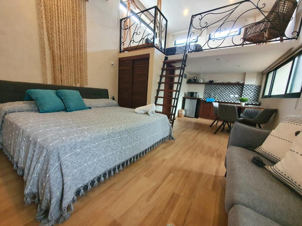 een slaapkamer met een bed, een trap en een bank bij Casa Luz Downtown Apartments in Tulum in Tulum