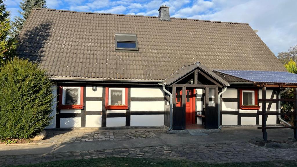 Biały i czarny dom z czerwonymi drzwiami w obiekcie Zur alten Eiche w mieście Guhrow
