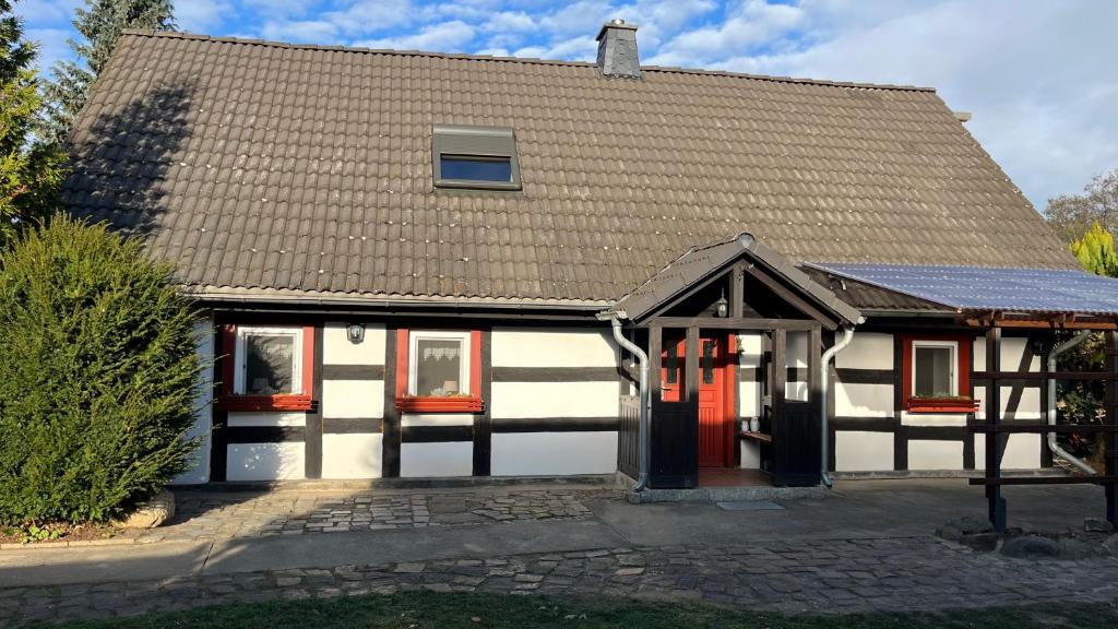 a white and black house with a red door at Zur alten Eiche in Guhrow