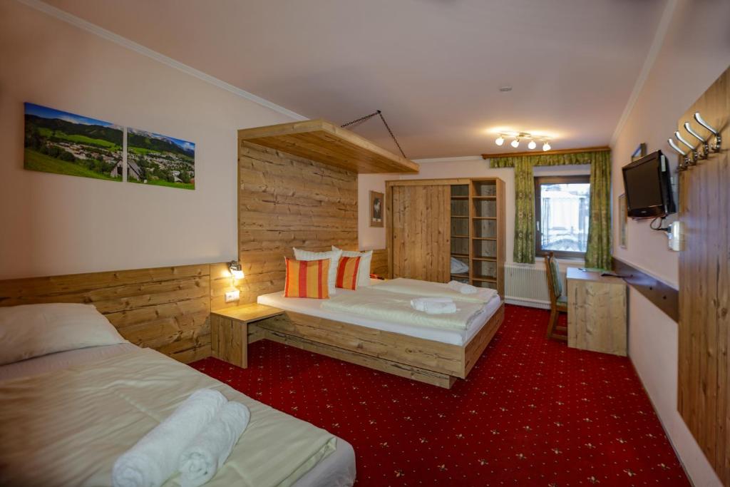 a hotel room with two beds and a television at Kirchenwirt Schladming in Schladming