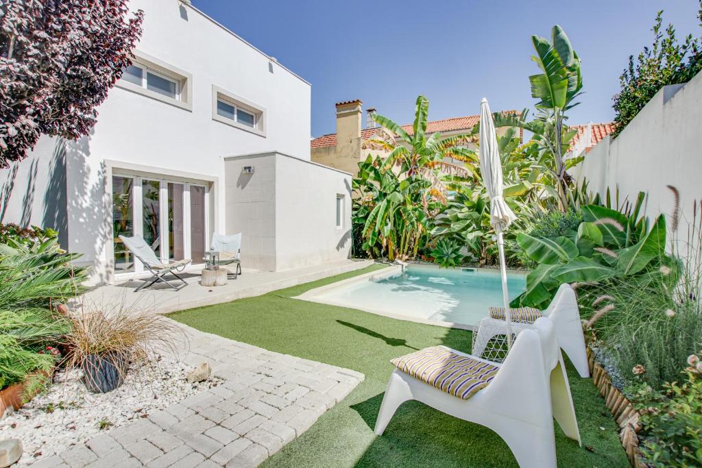 um quintal com uma piscina com uma cadeira e um guarda-sol em White and Light House em Costa da Caparica