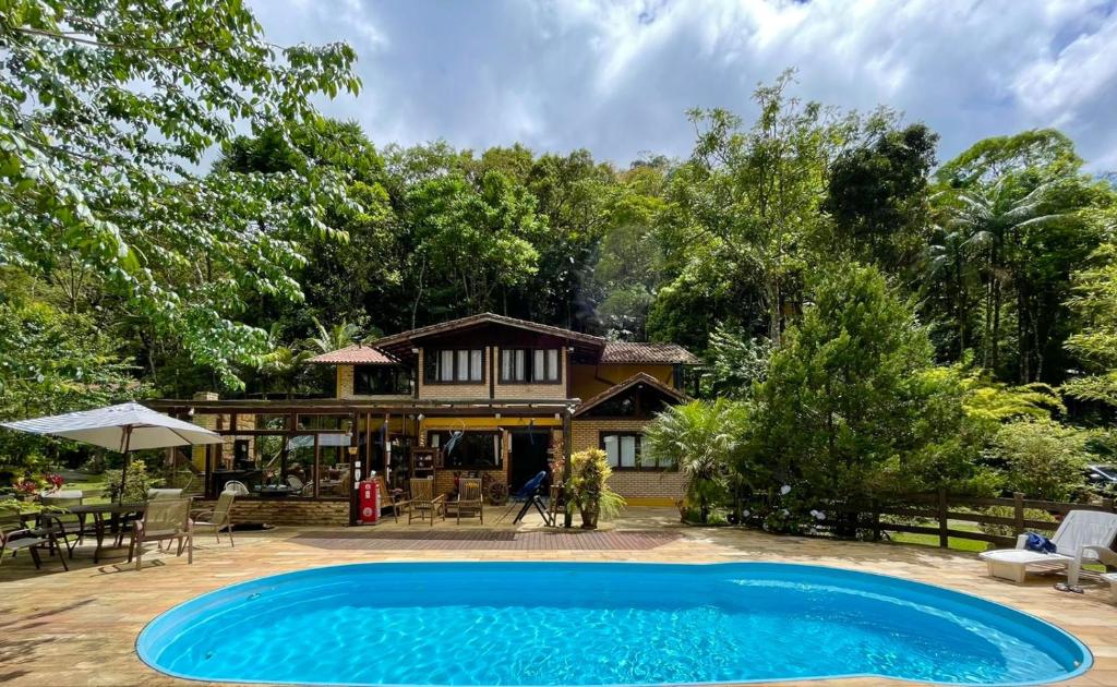 una casa con piscina frente a ella en Arara Azul en Nova Friburgo
