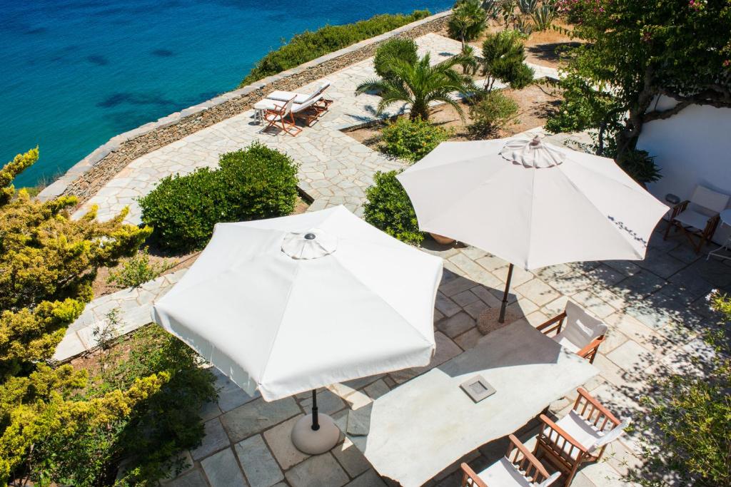 twee witte parasols op een patio naast het water bij Villa Celestina, Great for Privacy and Seclusion in Chrisopigi