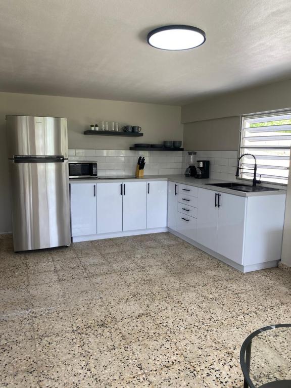 a kitchen with white cabinets and a stainless steel refrigerator at Casa Isabela En Cabo Rojo in Cabo Rojo
