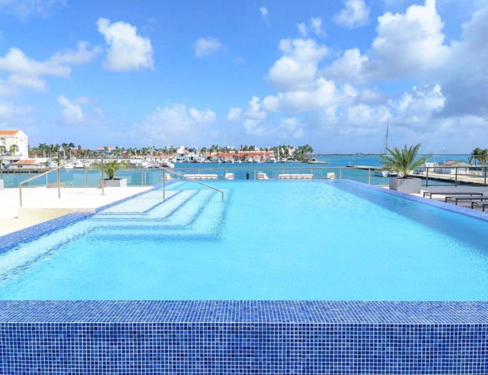 a large swimming pool with a view of the water at Stylish luxury condo, central location, ocean view, pool, gym in Oranjestad
