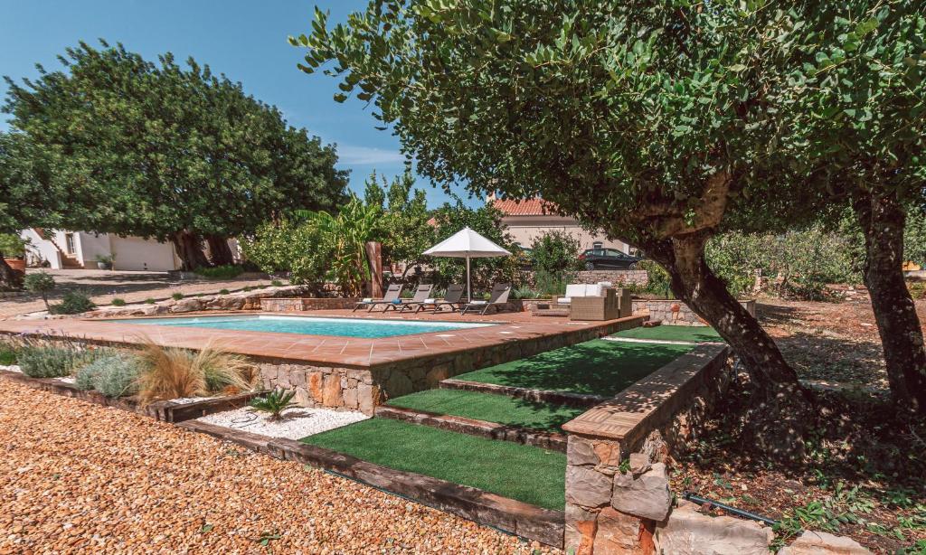 un patio trasero con piscina y un árbol en Monte 3 Alfarrobeiras, en São Brás de Alportel
