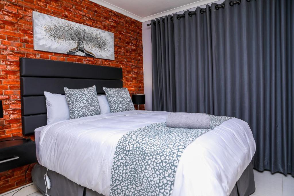 a bedroom with a bed and a brick wall at Delux Guesthouse in Volksrust