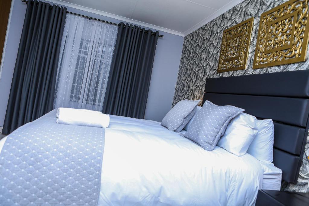 a bedroom with a white bed and a window at Delux Guesthouse in Volksrust