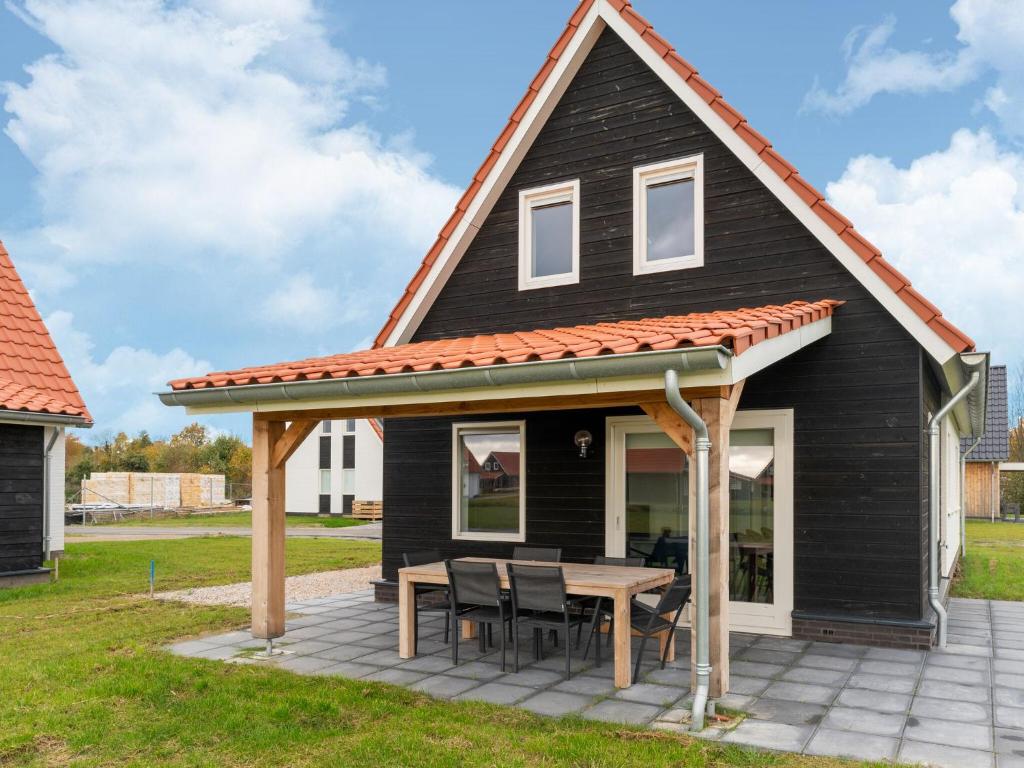 a black house with an orange roof and a picnic table at Beautiful Holiday Home in Scherpenisse with Terrace Garden in Scherpenisse