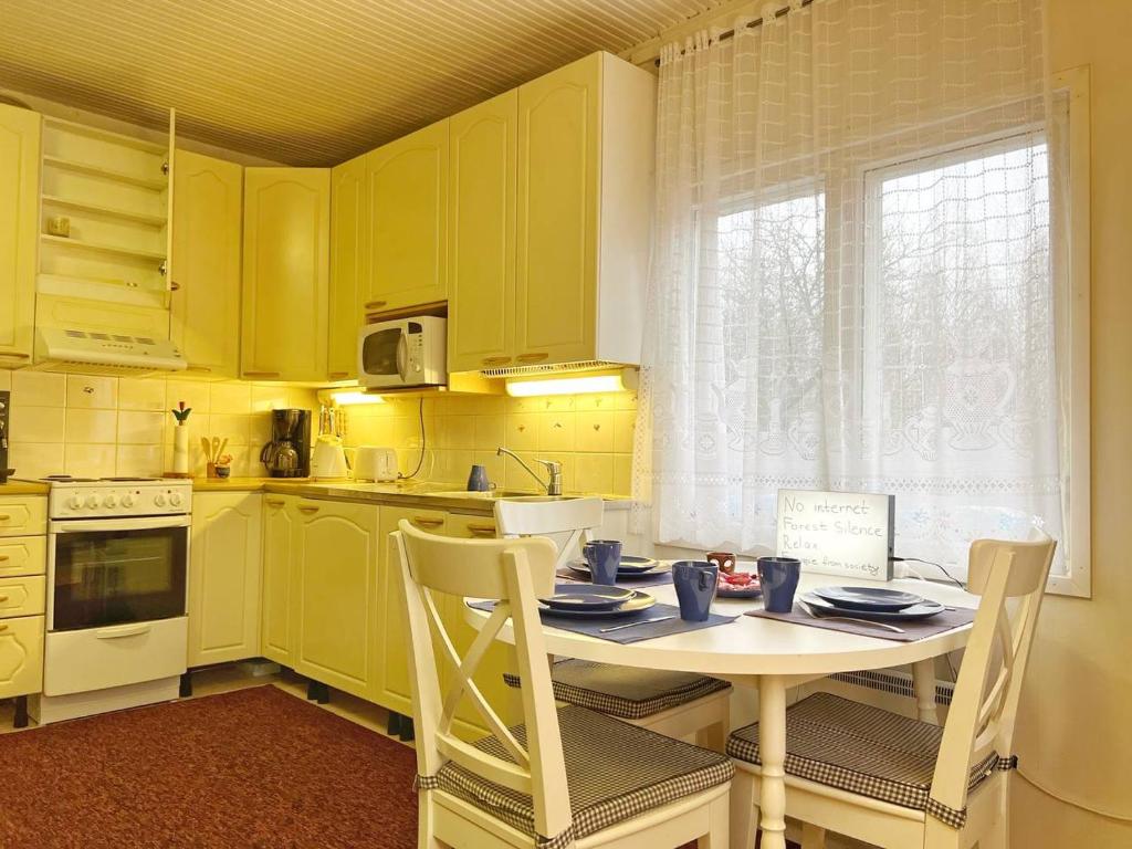 a kitchen with yellow cabinets and a table and chairs at Finnish house near the forest in Lappeenranta