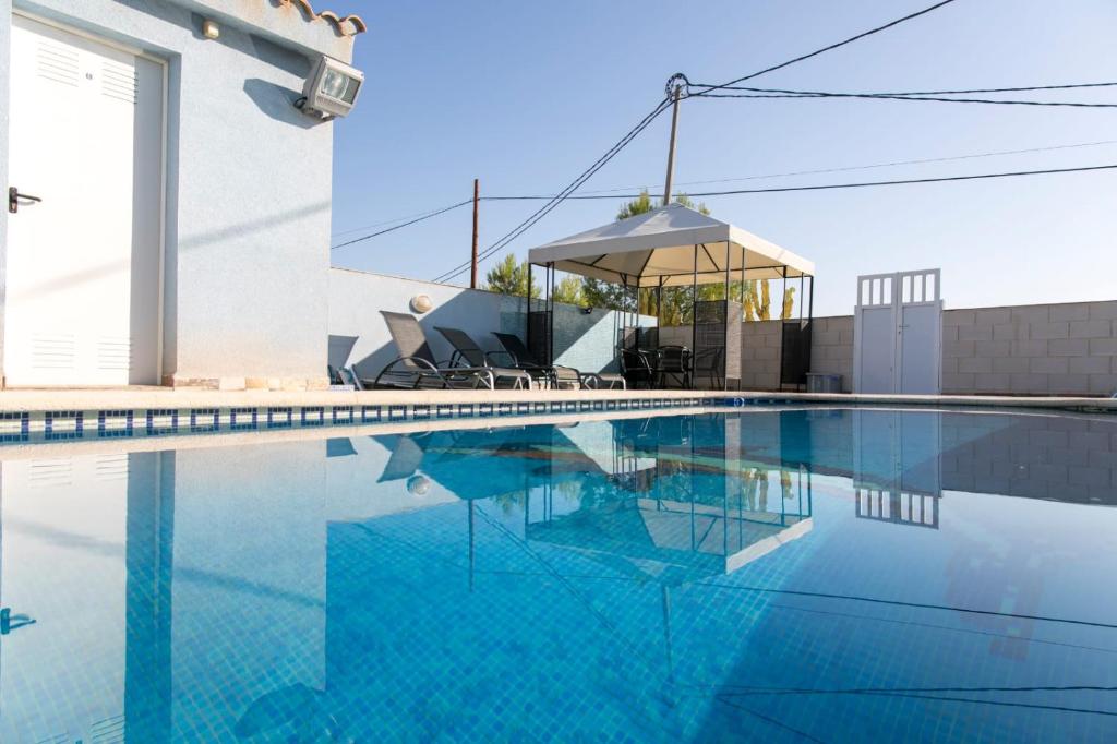 a swimming pool with a gazebo next to a house at El Rincón De Resu in Los Baños