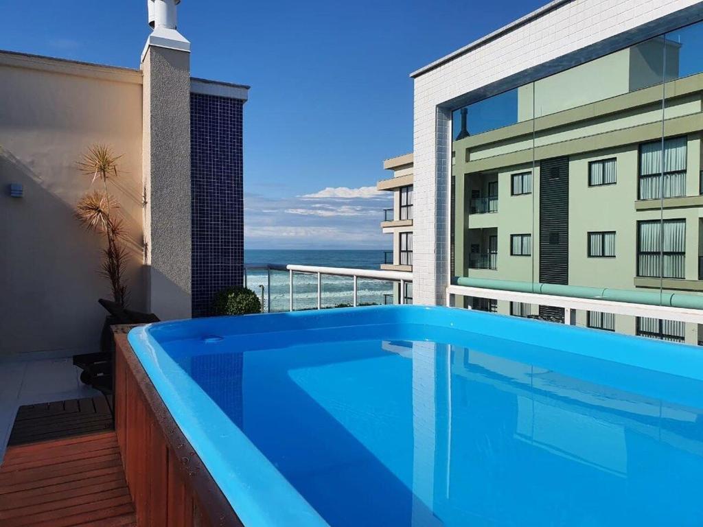una grande piscina blu sul balcone di un edificio di ANSNEGOCIOS DUPLEX FRENTE PRAIA MARISCAL 205 Palm a Bombinhas