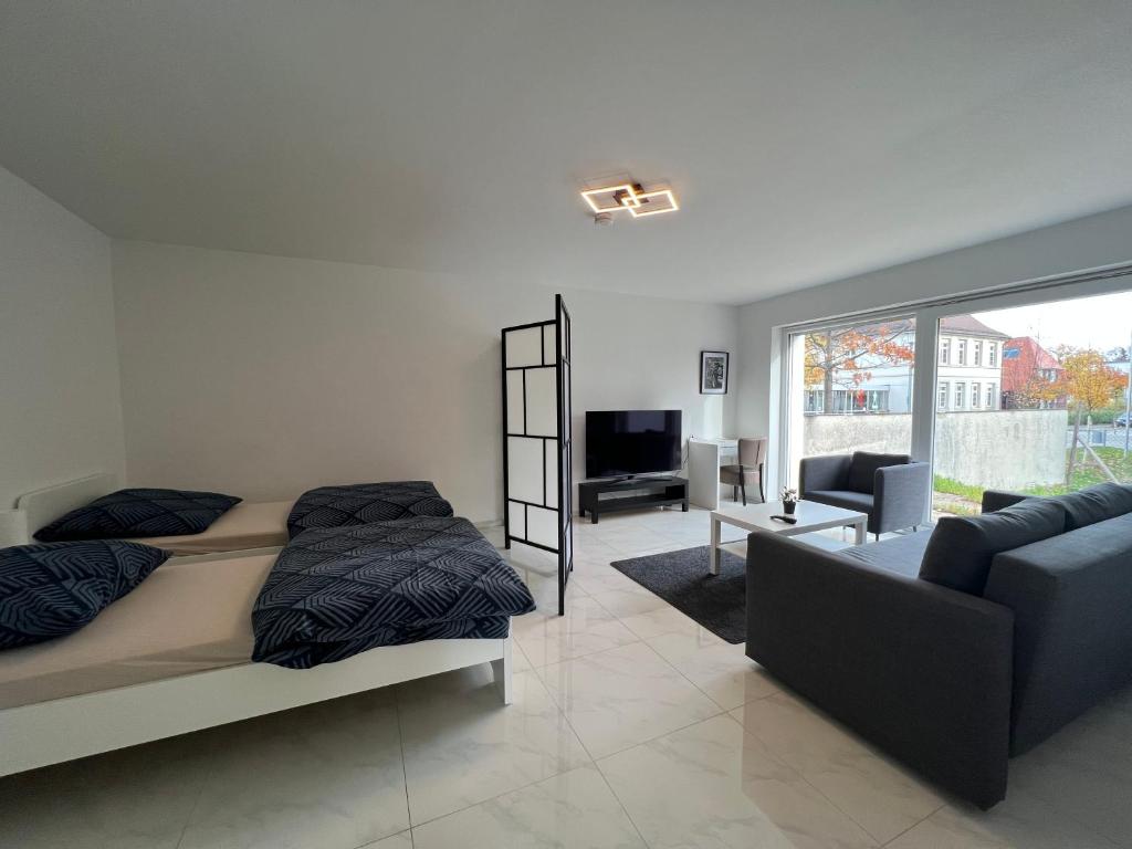 ein Schlafzimmer mit einem Bett, einem Sofa und einem TV in der Unterkunft Wunderschöne Unterkunft mit Terrasse - 24h7t Checkin in Karlsruhe