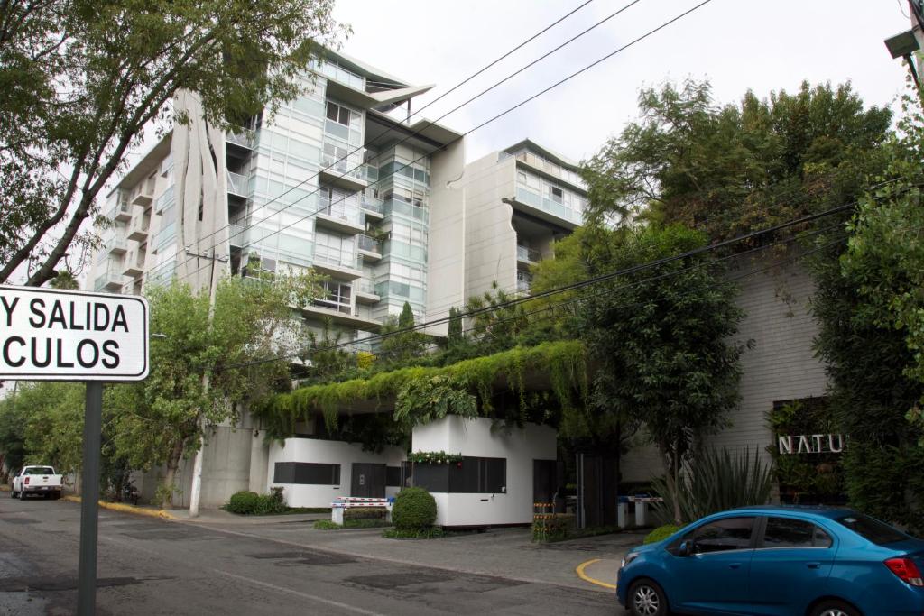 a blue car parked in front of a building at Habitación confortable dentro departamento Natura in Mexico City