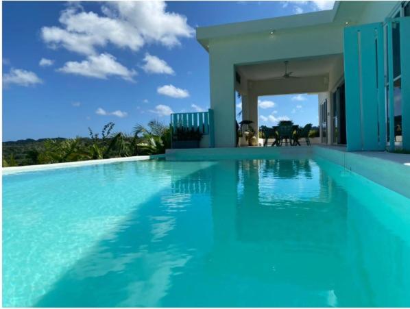 a large blue swimming pool with a house at VistaLinda, Villa ANCA in Río San Juan