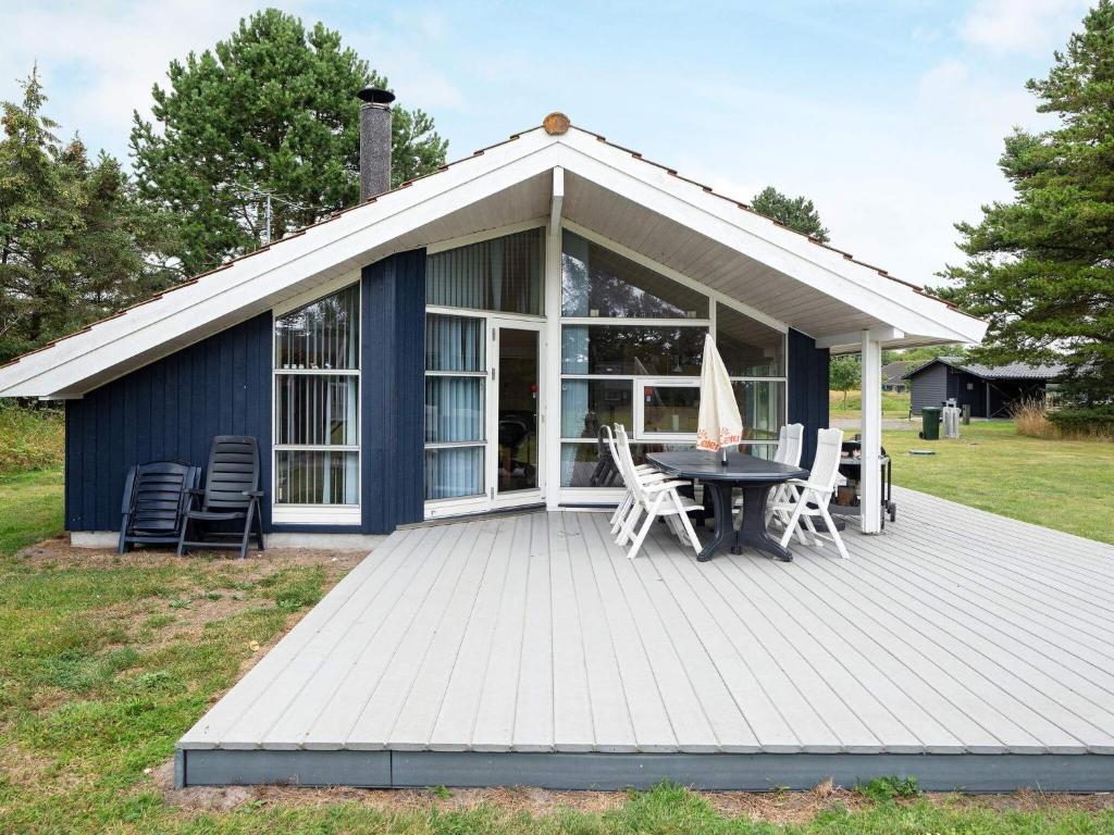 a blue cottage with a table and chairs on a deck at Three-Bedroom Holiday home in Rødby 6 in Kramnitse