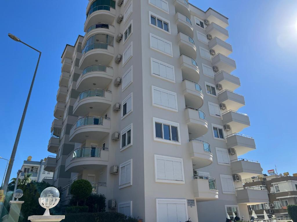 ein hohes weißes Apartmenthaus vor einem blauen Himmel in der Unterkunft Cleopatra Uygun Apartment in Alanya