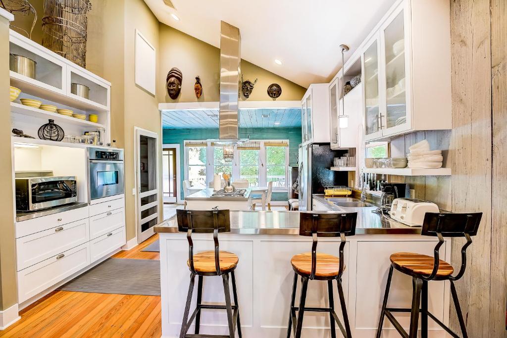 a kitchen with white cabinets and bar stools at Garden Home in Austin