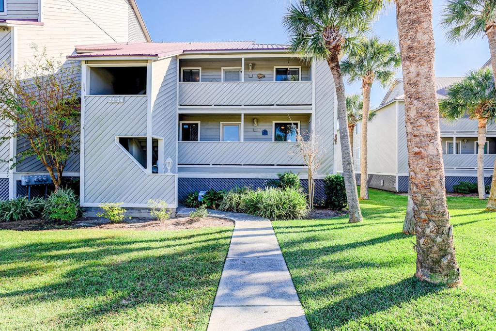 a walkway in front of a house with palm trees at Mariners Cay 23 in Folly Beach