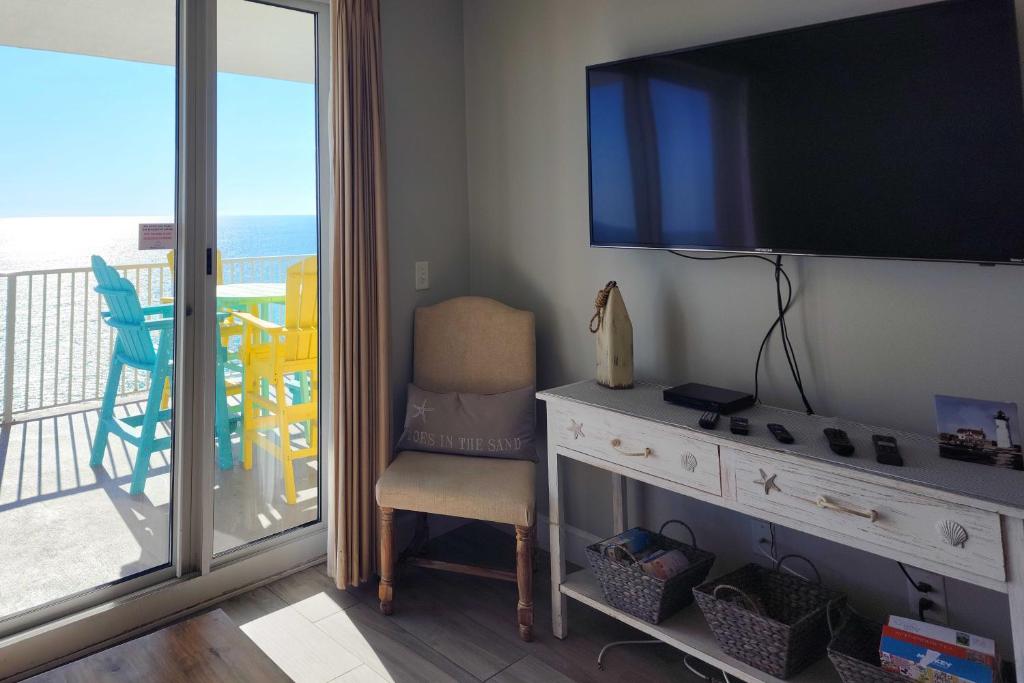 a room with a tv and a chair and a balcony at Sea Kastle in Panama City Beach