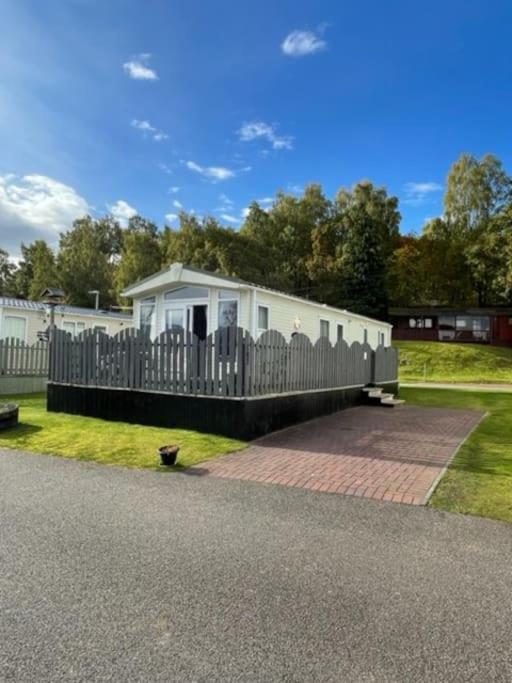 a house with a fence on the side of the road at Freedom Lodge-Aviemore with FREE Starlink Superfast broadband 150mbps - All bedding and towels included - Pet Free in Aviemore