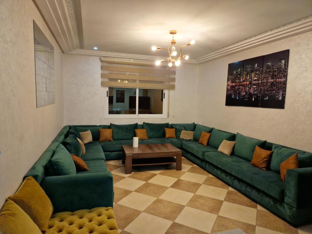 een woonkamer met een groene bank en een tafel bij Residence la Cornich nador in Nador