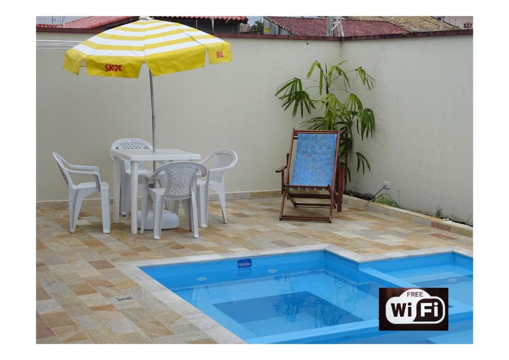 een zwembad met een tafel en stoelen en een parasol bij Casa Peruibe. in Peruíbe