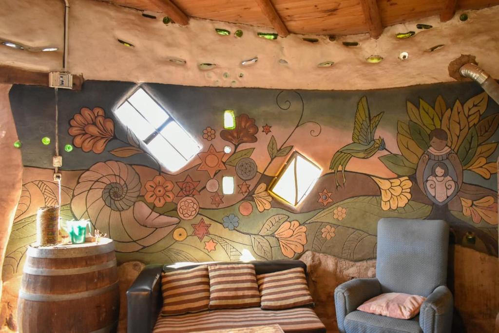 Habitación con sofá y pared pintada. en Ecohostel Tay Pichin en San Marcos Sierras