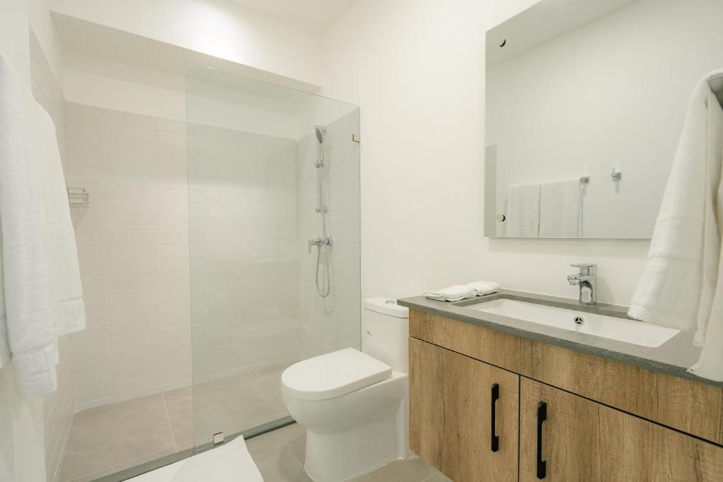 a white bathroom with a toilet and a sink at Lumina at Flats Punta Cana Village in Punta Cana