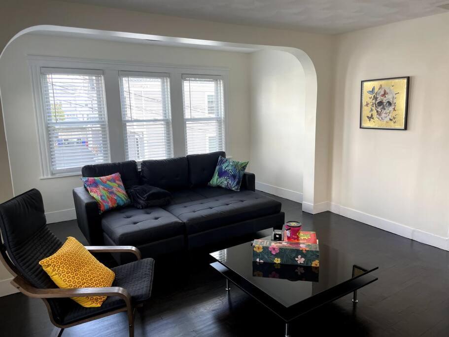 a living room with a black couch and a table at Modern Three Bedroom Condo - Boston in Stoneham