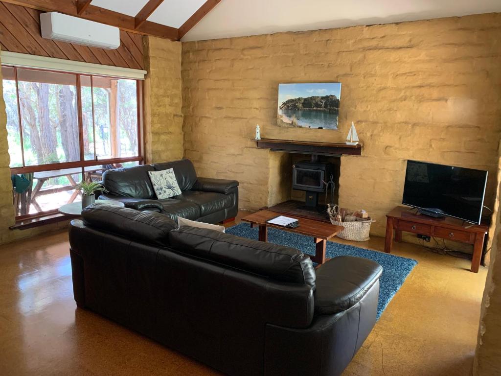 sala de estar con sofá de cuero y chimenea en Denmark Forest Retreat, en Denmark