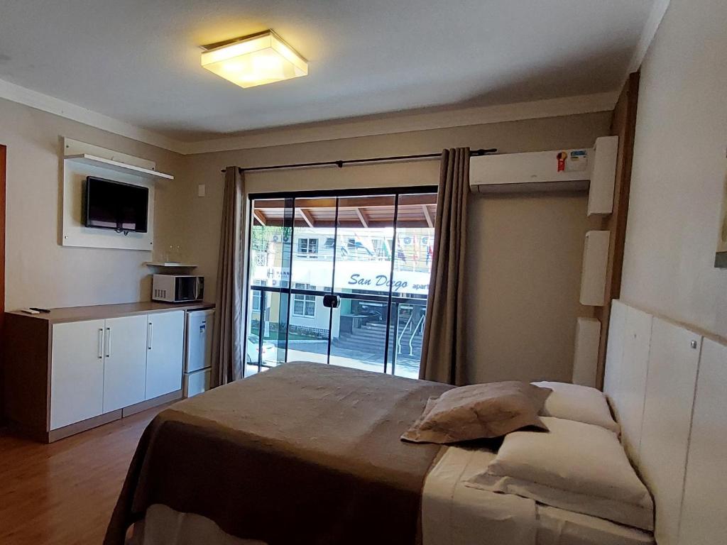 Pousada Casa Da Praia في فلوريانوبوليس: غرفة نوم بسرير وباب زجاجي منزلق
