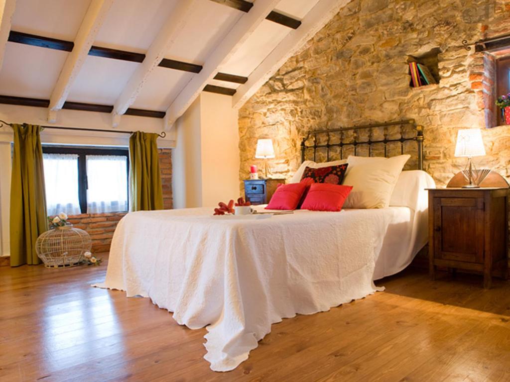 a bedroom with a large bed with a stone wall at Posada Santa Ana in Suances