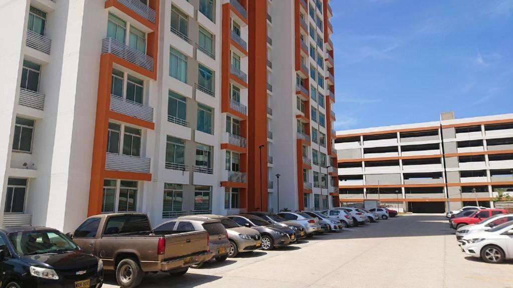 una fila de autos estacionados en un estacionamiento frente a un edificio en Barranquilla Gran Apartamento, en Puerto Colombia
